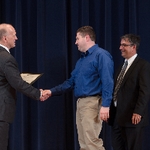 Doctor Potteiger shaking hands with an award recipient in a blue shirt